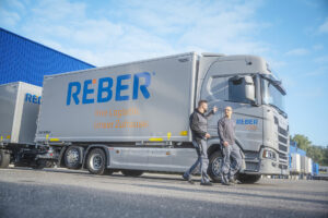 Ein LKW mit zwei Mitarbeitern der REBER Logistik - Unser Kunde für Markenbildung