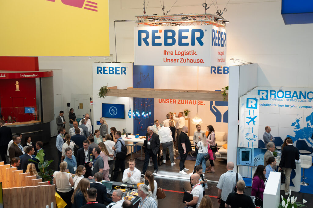 Der Stand von REBER auf der transport logistic Messe in München 2025 von weiter weg mit Besuchern.