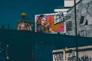 Straßenkunst in England, zeigt eine Frau im Graffiti Stil, die Leute zum Kauf aufruft.