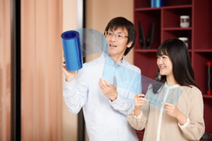 Kampagnenmotiv: Zwei Mitarbeitende von Mitsui Chemicals Europe präsentieren innovative Kunststofffolie im Labor.