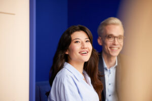 Kampagnenmotiv: Zwei Mitarbeitende von Mitsui Chemicals Europe in einem Meeting, lächelnd vor blauem Hintergrund.