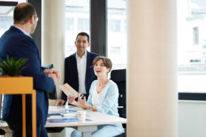 itarbeitende im Gespräch an einem Stehtisch, Mitsui Chemicals Europe Büro mit hellen Fenstern.